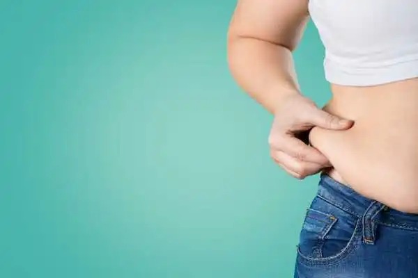 Image of woman pinching her love handles to show weight gain Clydebank